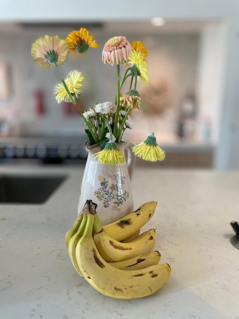 bloemen-banaan-ethyleengas-boeket-houdbaarheid Een half verdord boeket bloemen naast een tros bananen – een combinatie die de houdbaarheid van bloemen kan verkorten door ethyleengas
